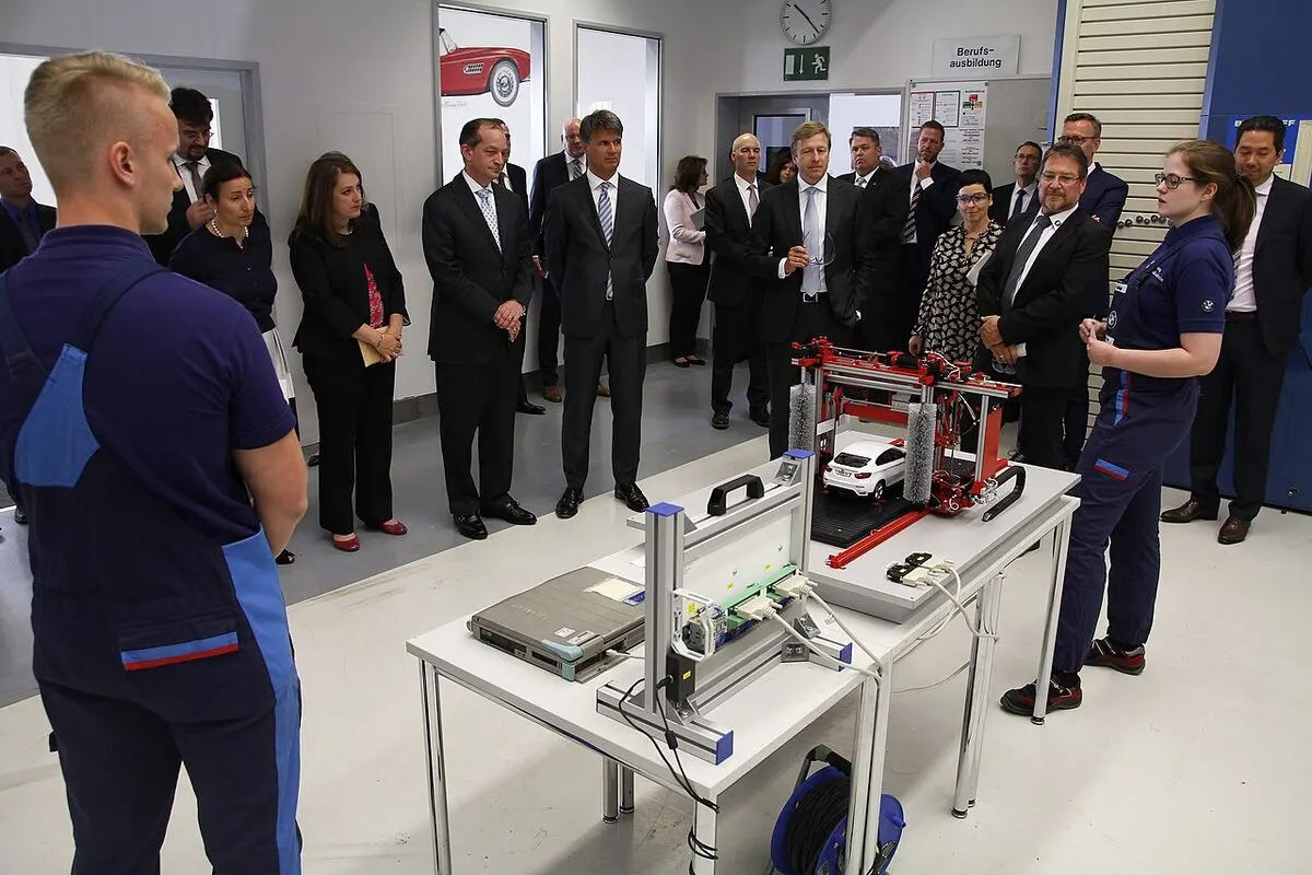 Visitors and trainees around a mechatronics teaching rig in a company apprenticeship workshop